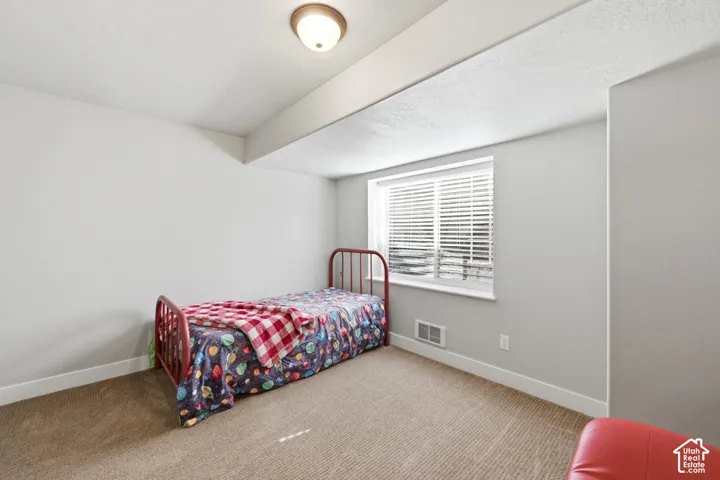 Neutral wall tones, wall-to-wall carpeting, window with horizontal blinds, and a dome-style ceiling light fixture