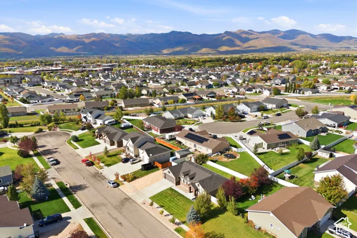 Aerial perspective of suburban residential neighborhood featuring asphalt paved streets, single-family dwellings with fenced rear yards, and expansive mountain range backdrop