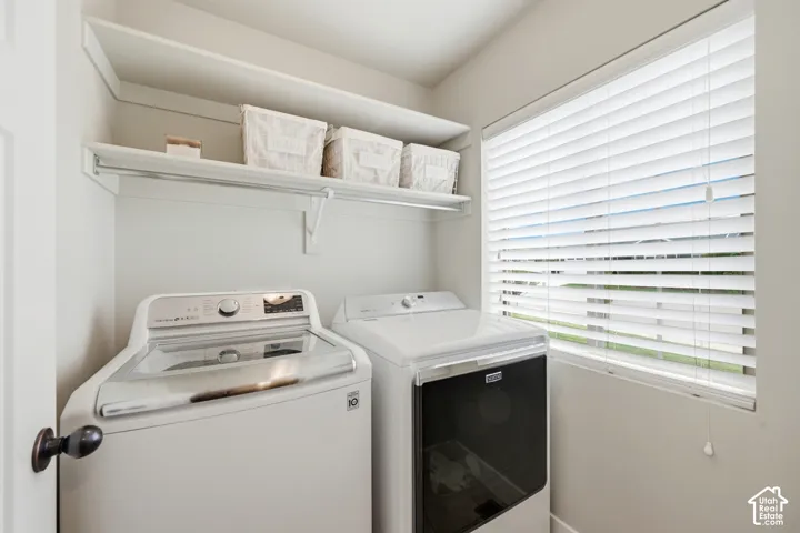 Laundry space featuring integrated wall-mounted shelving with a hanging rod and a window equipped with horizontal slat blinds