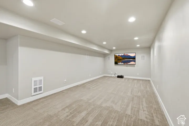 Neutral wall palette featuring recessed lighting, wall-integrated speakers, and carpeted flooring