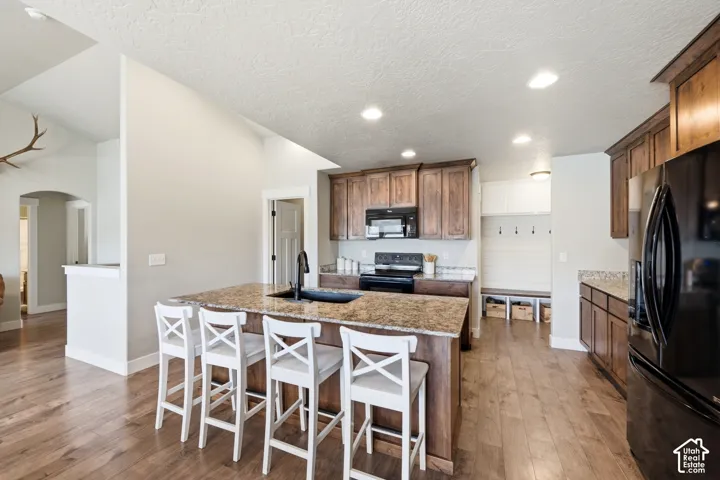 Kitchen featuring a large center island with a stone-finish countertop, wood cabinetry, recessed lighting, and a built-in mudroom nook