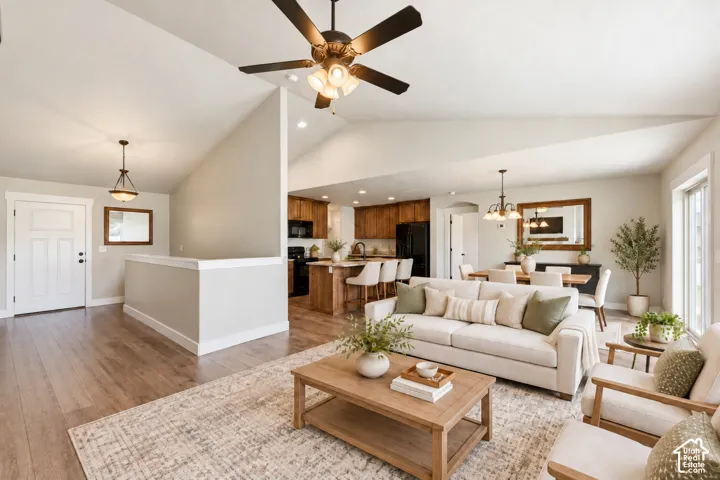 Vaulted ceilings, wood-finish flooring, kitchen island with built-in cabinetry, and multi-light ceiling fan