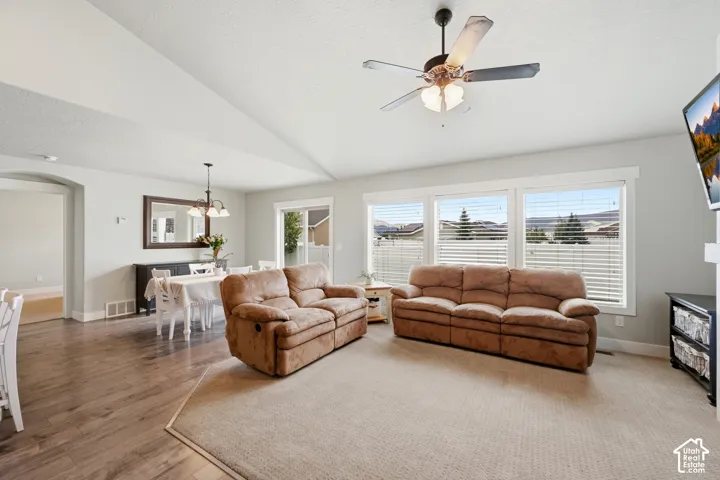 Vaulted ceilings, wood-finish flooring, recessed lighting, ceiling fan with light kit, and large windows with horizontal blinds