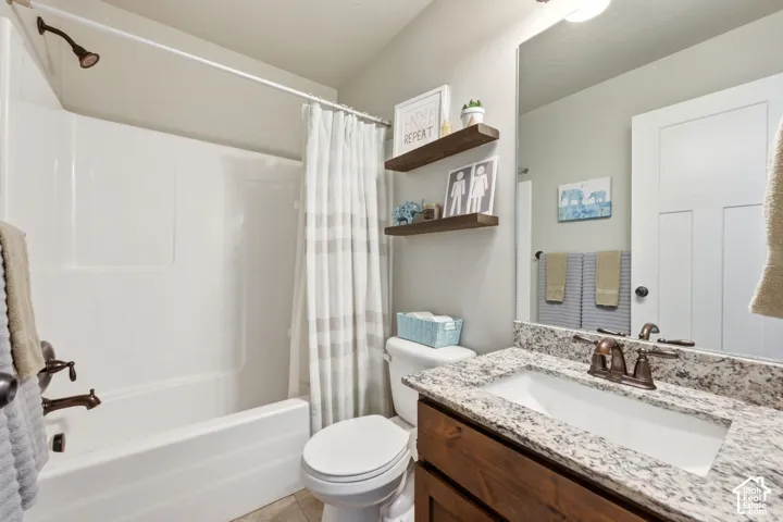 Bathroom vanity featuring a stone-composite countertop, undermount sink, and oil-rubbed bronze faucet hardware, paired with a shower-tub combination and two wall-mounted wood floating shelves