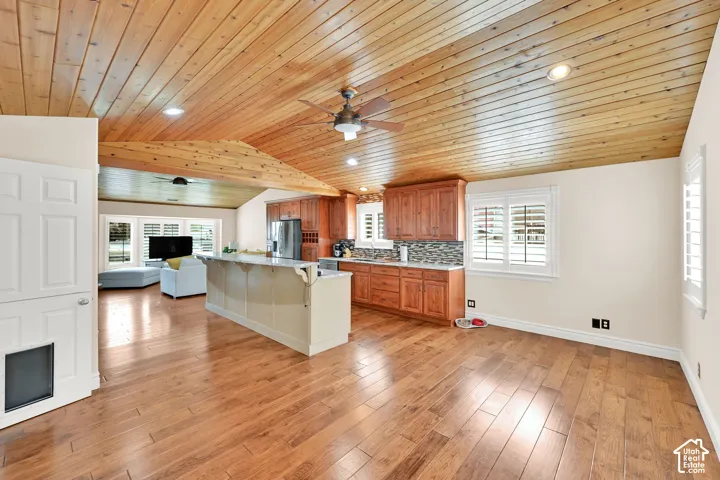 Vaulted wood-paneled ceiling, wood-finish flooring, kitchen island with countertop, wood cabinetry, and plantation shutters