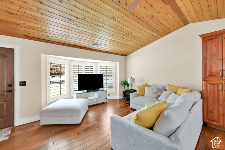 Vaulted wood-paneled ceiling, wood-finish flooring, bay windows with plantation shutters, built-in wood cabinetry, and a solid wood entry door