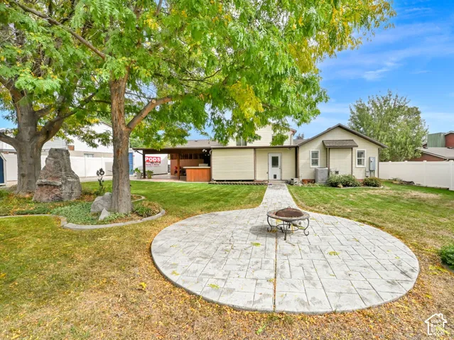 Expansive backyard featuring a circular stamped concrete patio, established trees, and a covered outdoor living area