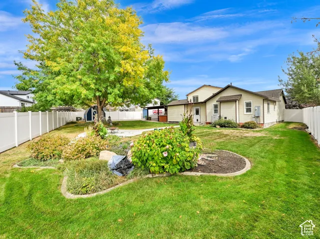 Expansive backyard featuring a manicured lawn, established landscaping, and a privacy fence