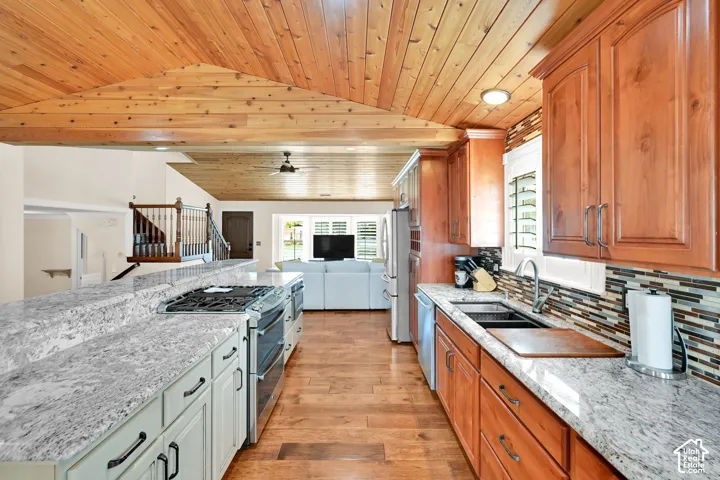 Vaulted wood-paneled ceiling, wood-finish flooring, two-tone cabinetry, stainless steel appliances, and light-toned countertops