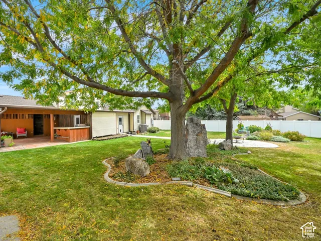 Expansive backyard with a covered patio, an outdoor bar area, a concrete patio, and mature trees