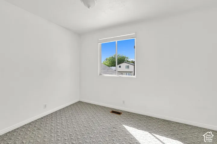 Patterned carpet flooring with a window featuring blinds
