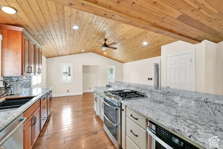 Vaulted wood-paneled ceiling with recessed lighting, wood-finish flooring, granite countertops, stainless steel appliances, and a mosaic tile backsplash