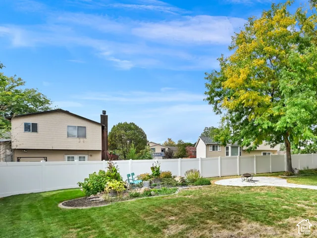 Expansive yard with mature trees, a detached storage shed, white privacy fencing, a paved patio area, and established landscaping