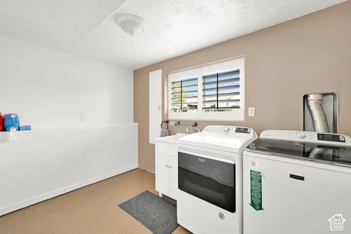 Laundry area featuring a ceiling-mounted light fixture, a window with horizontal blinds, and a utility sink with white cabinetry
