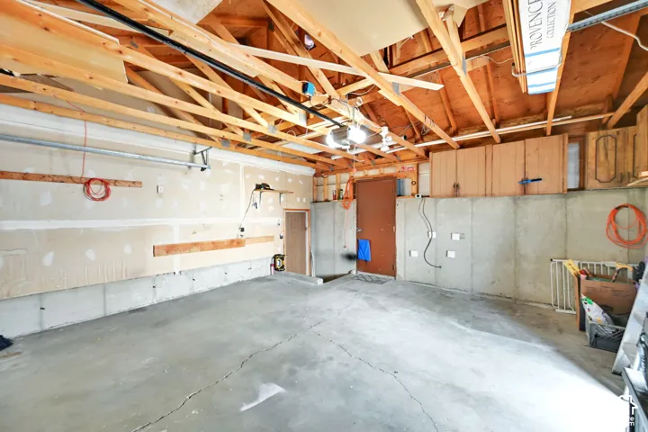 Spacious garage interior featuring exposed wood beam ceiling with skylights, concrete flooring, and substantial storage capacity