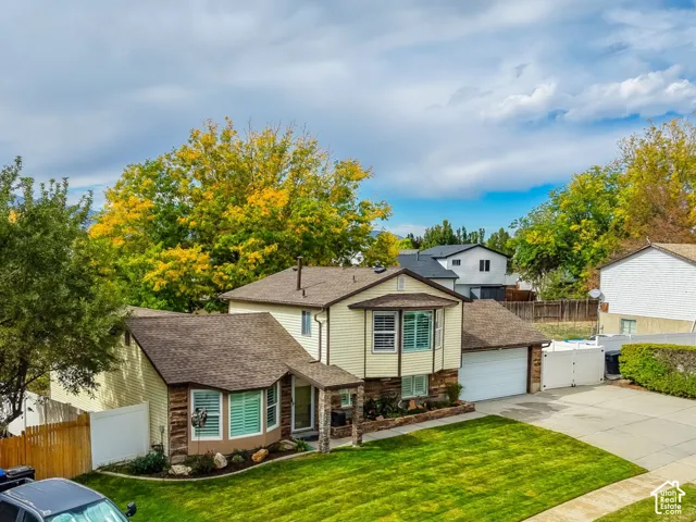 Two-story residence featuring a two-car garage, manicured front lawn, and mature landscaping