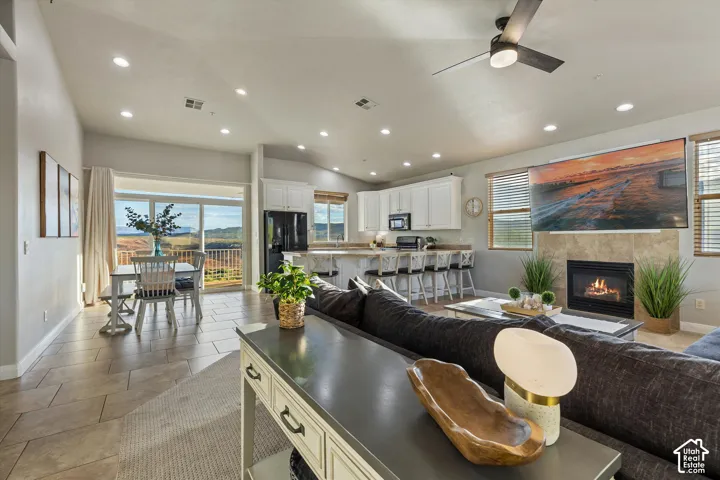 Living Room: Vaulted ceilings and recessed lighting flow from the living room to the kitchen, the dining area, and the deck view beyond.