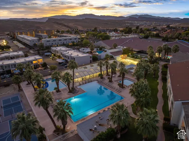 Aerial: The Las Palmas amenity center at sunset, with a lap pool, the giant double waterslide, the indoor pool enclosure, and pickleball courts.