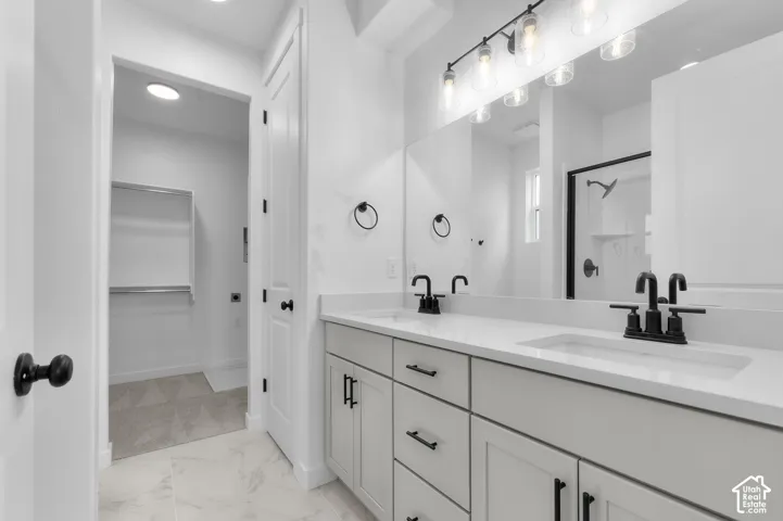 Dual-sink vanity with a quartz countertop, matte black fixtures, shakers-style cabinetry, and large-format tile flooring