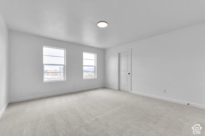 Neutral interior featuring wall-to-wall carpeting, dual windows, and a multi-panel interior door