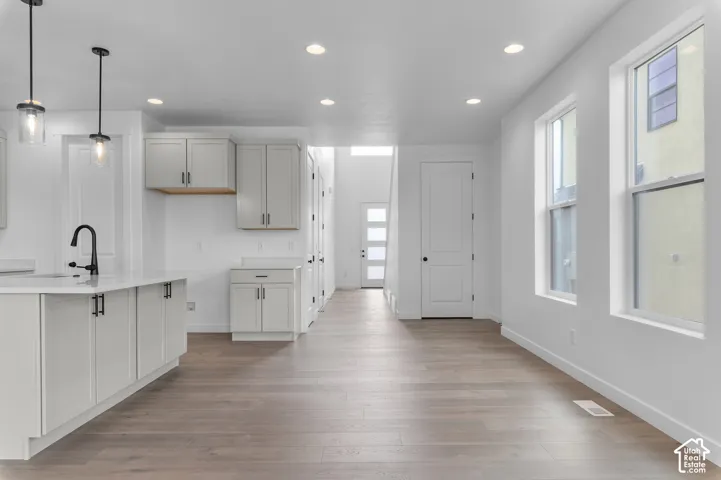 Kitchen featuring a quartz-topped island, shaker-style cabinetry, matte black hardware, recessed ceiling lighting, and wood-finish flooring