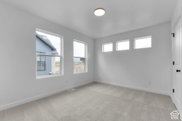 Room featuring neutral wall-to-wall carpeting, three upper-level transom windows, two large windows with exterior exposure, and a flush-mount circular ceiling light