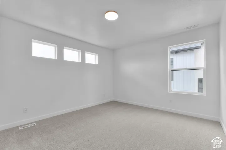Neutral-toned carpeting, triple horizontal transom windows, one rectangular window, and a flush-mount circular ceiling fixture