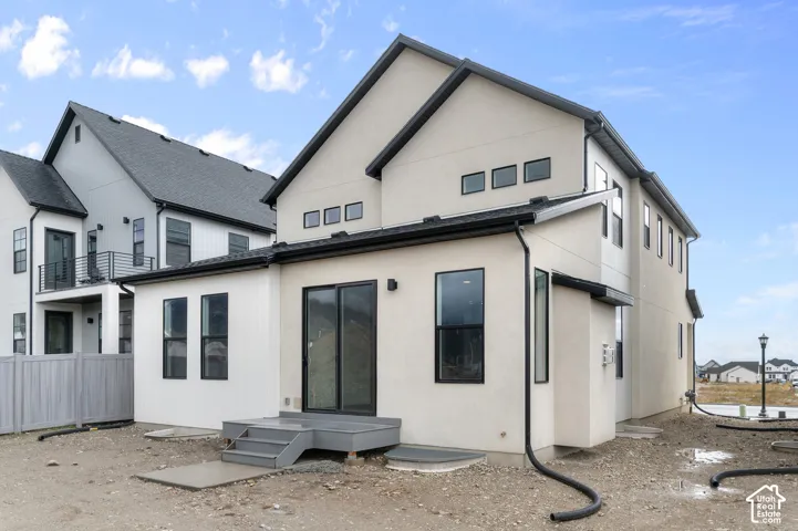 Multi-level exterior featuring light-toned stucco and vertical board-and-batten siding, black-trimmed windows, a gabled roofline, and a raised wooden deck with exterior access