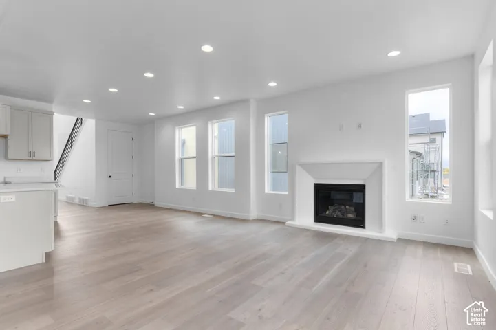 Open interior featuring wood-finish flooring, recessed lighting, and a fireplace with a custom-built surround