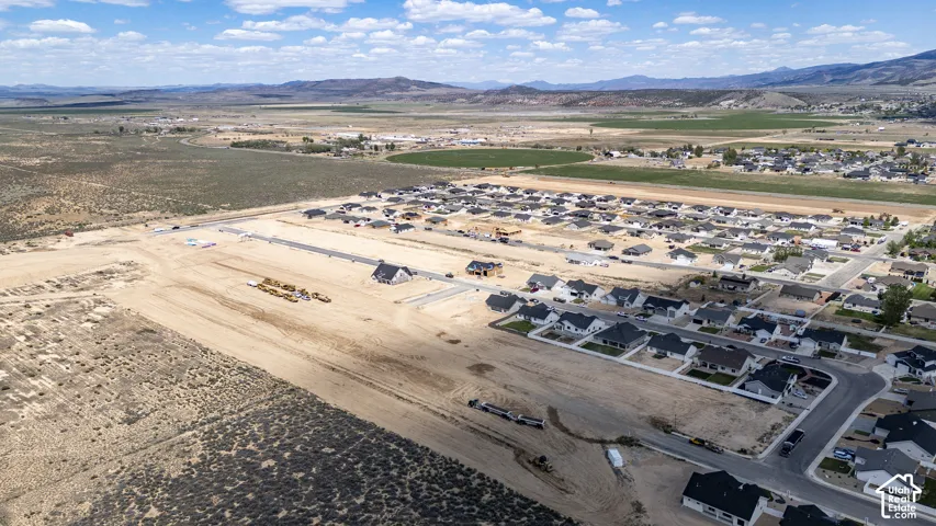 Aerial perspective of a development site featuring paved roads, utility infrastructure, and mountain topography