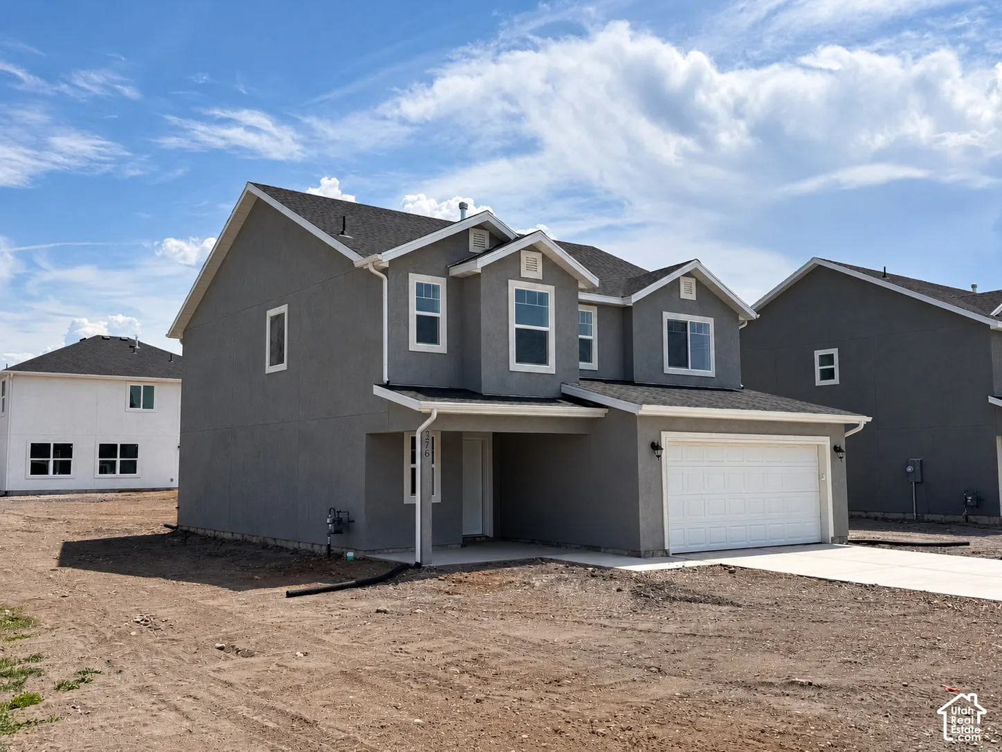 Two-story exterior featuring a stucco facade, gable roofline, multi-pane windows, and a two-car garage
