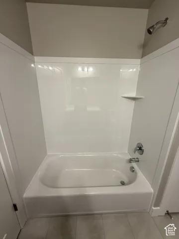 Bathtub and shower surround featuring a white acrylic finish, integrated shelving, a single-handle chrome pressure-balance valve, and a wall-mounted shower head
