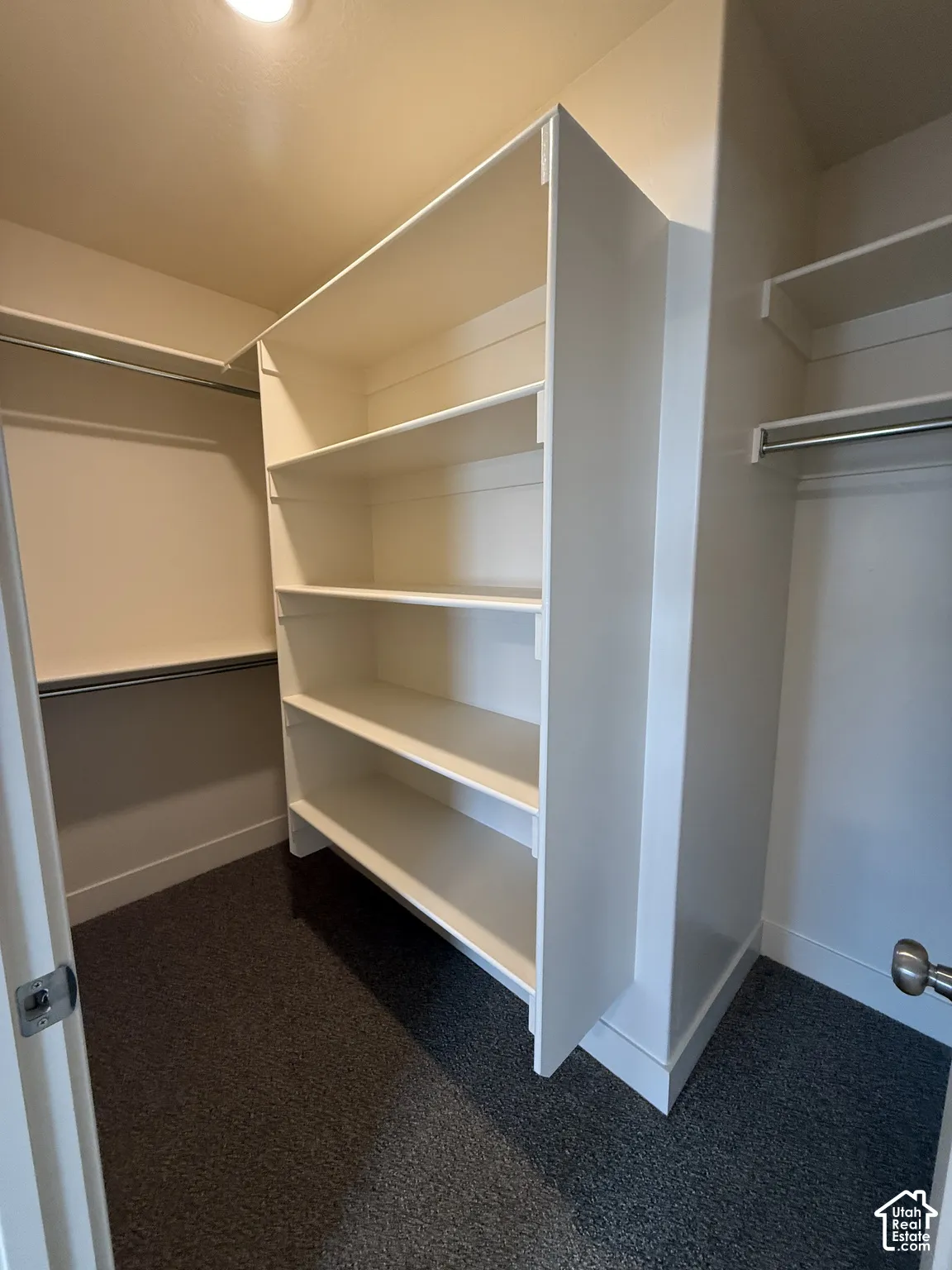 Walk-in closet featuring white built-in shelving, dual metal hanging rods, and neutral carpeting