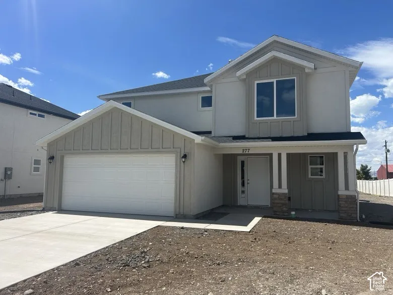 Two-story exterior featuring a mix of stucco and vertical siding, covered front entryway, concrete driveway, and stone veneer accents
