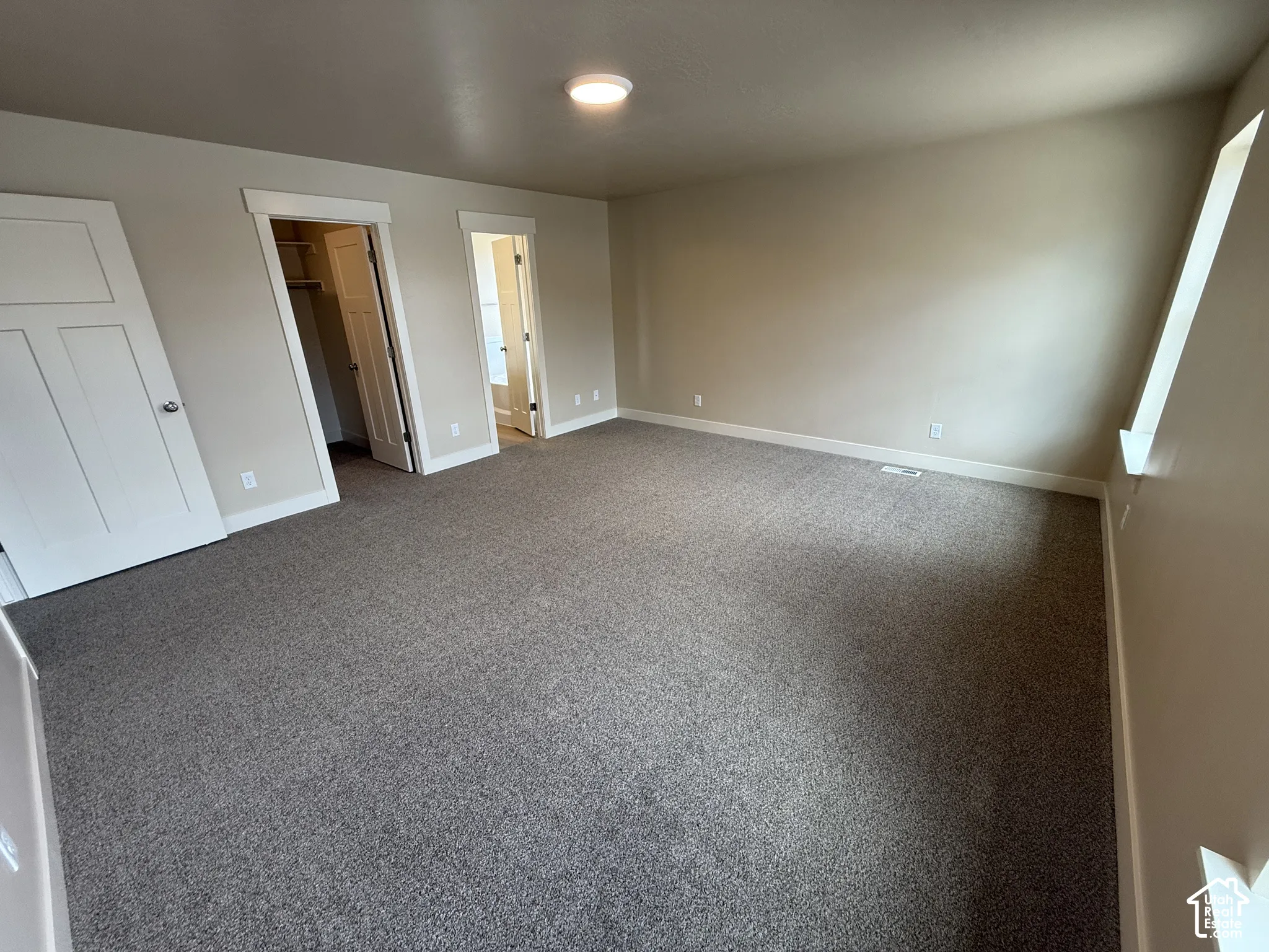 Neutral-toned interior featuring wall-to-wall carpeting, three-panel interior doors, recessed ceiling lighting, and natural light from a window sill