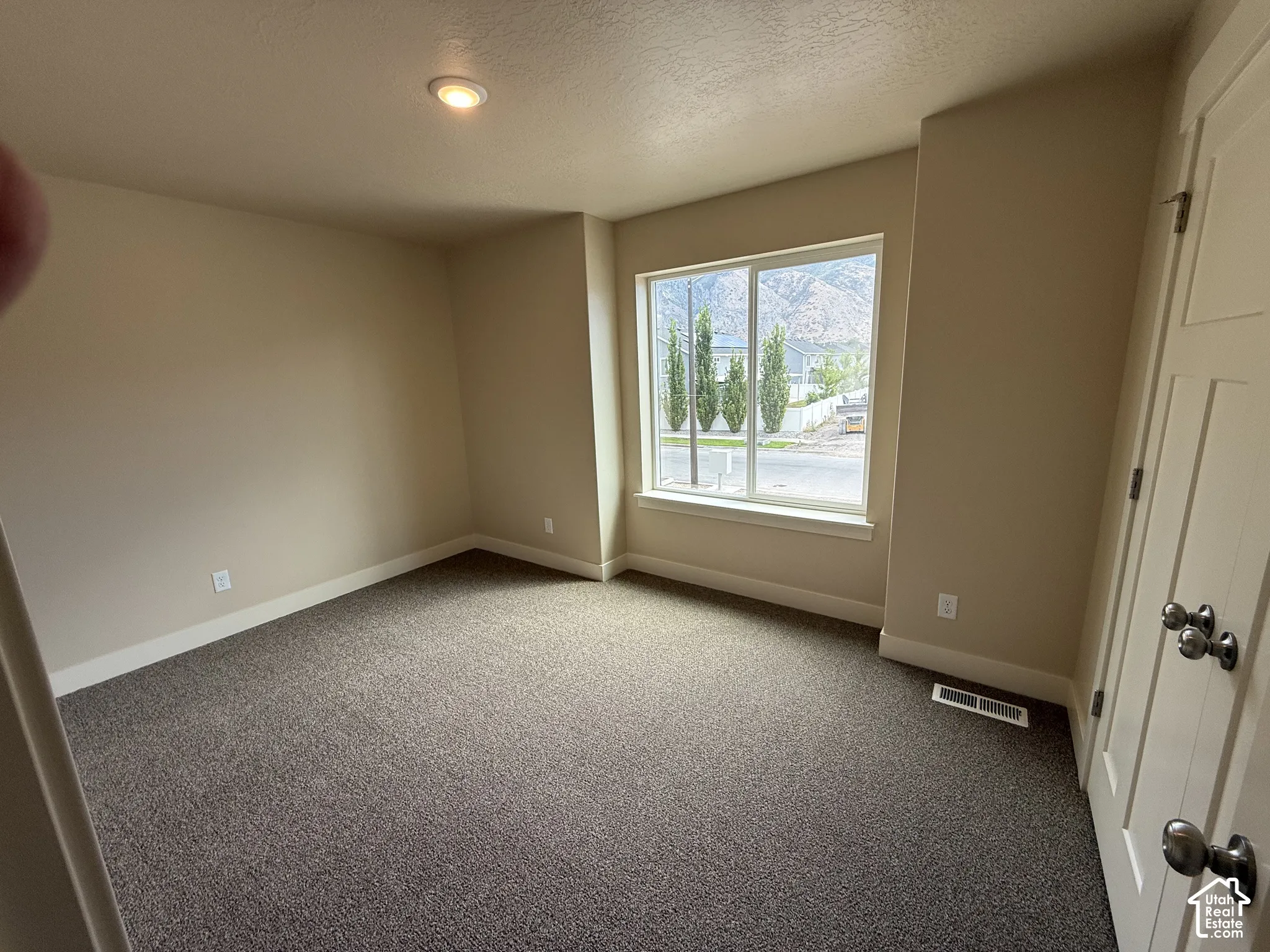 Neutral-toned interior space featuring wall-to-wall carpeting, recessed ceiling lighting, a sliding window with mountain scenery, and a paneled interior door