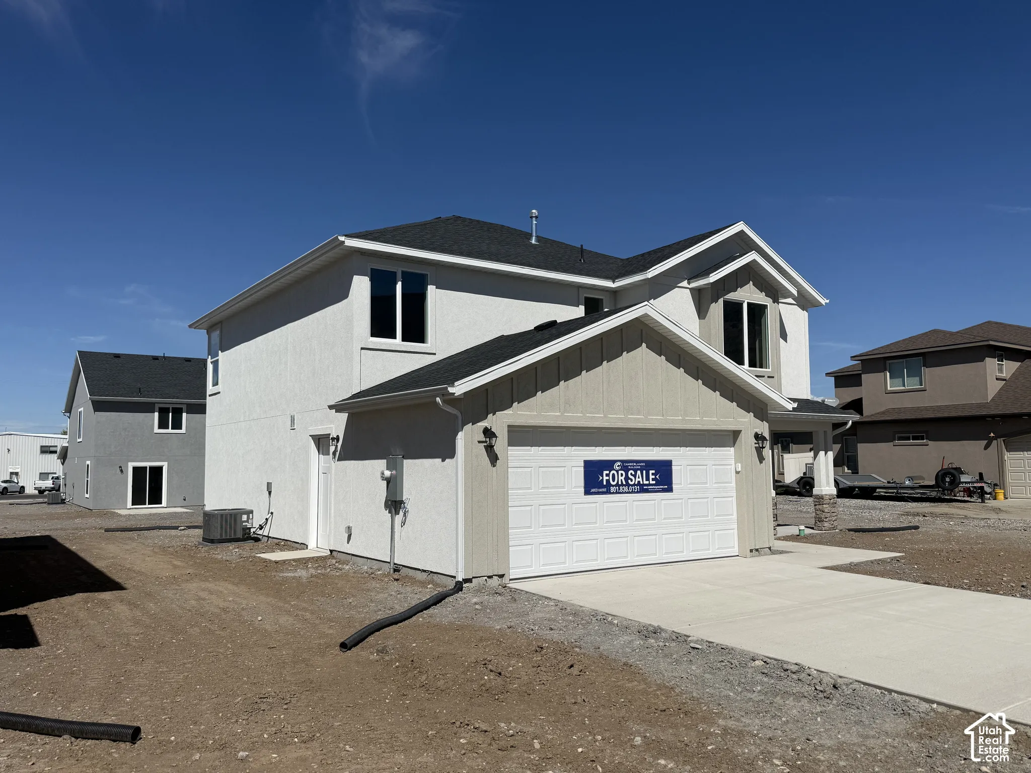 Two-story residence featuring a dual-tone stucco and vertical siding exterior, asphalt shingle roofing, attached two-car garage, and concrete driveway