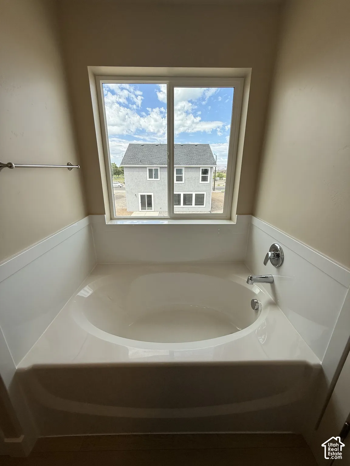 Built-in soaking tub with surround, chrome plumbing fixtures, and sliding window