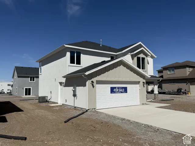 Two-story residence featuring a dual-tone stucco and vertical siding exterior, asphalt shingle roofing, attached two-car garage, and concrete driveway