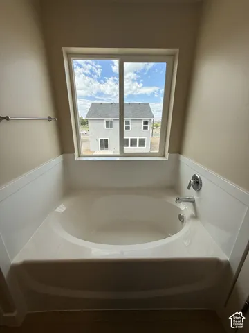 Built-in soaking tub with surround, chrome plumbing fixtures, and sliding window