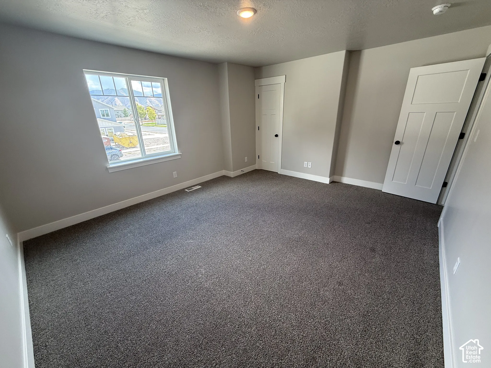 Neutral-toned room featuring plush wall-to-wall carpeting, shaker-style interior doors, and a single-hung window with a mountain backdrop