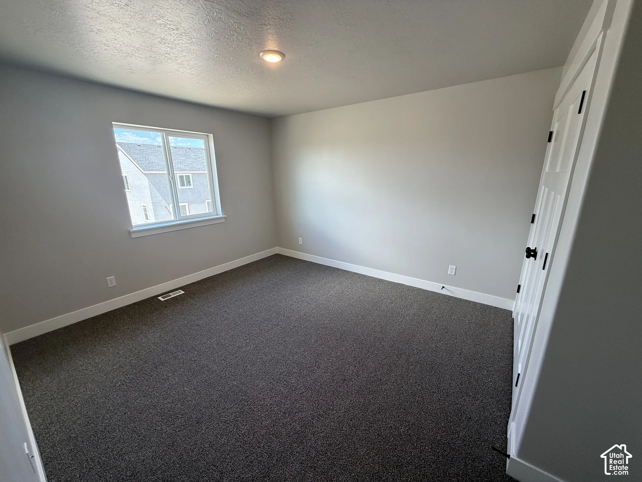 Room featuring neutral-toned carpeting, recessed ceiling lighting, a single-panel window, and a multi-panel door with dark hardware