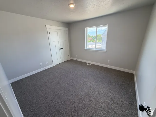 Neutral-toned interior featuring wall-to-wall carpeting, recessed ceiling lighting, a single-pane sliding window, and a closet with double-swing doors featuring matte black hardware