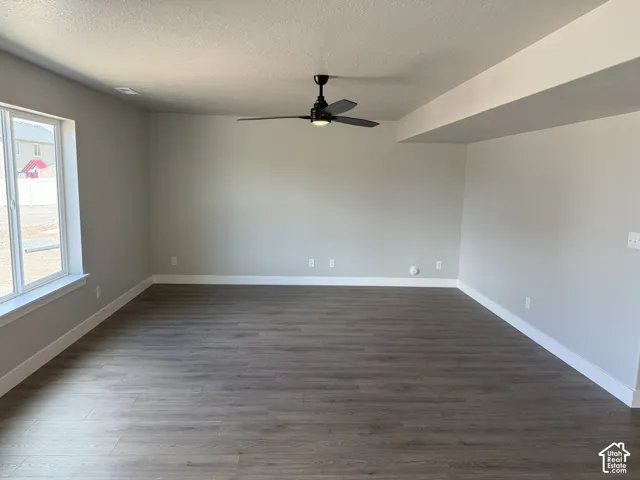 Neutral-toned interior featuring wood-finish flooring, a matte black ceiling fan, recessed lighting, and a large window with a white frame