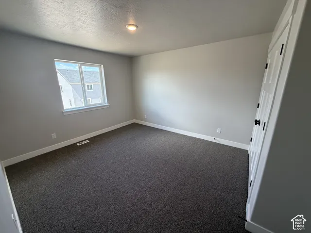 Room featuring neutral-toned carpeting, recessed ceiling lighting, a single-panel window, and a multi-panel door with dark hardware