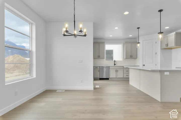 Open-concept kitchen featuring light-toned cabinetry, a quartz-topped island, wood-finish flooring, recessed lighting, and a multi-arm chandelier