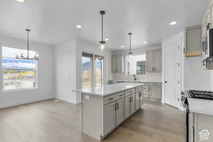 Kitchen featuring an expansive center island with quartz countertops, custom shaker-style cabinetry, matte black hardware, recessed lighting, and wood-finish flooring