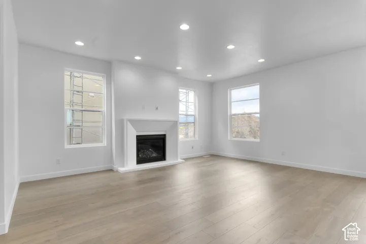 Living area featuring wood-finish flooring, recessed lighting, and a fireplace with a white surround