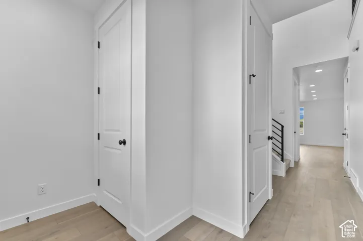 Wood-finish flooring, two-panel interior doors with matte black hardware, and recessed lighting