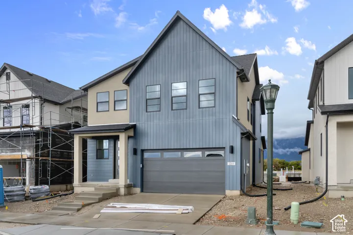 Two-story exterior featuring a mix of vertical board-and-batten and smooth-finish siding, a covered entryway, a dual-paneled garage door with windows, and a concrete driveway